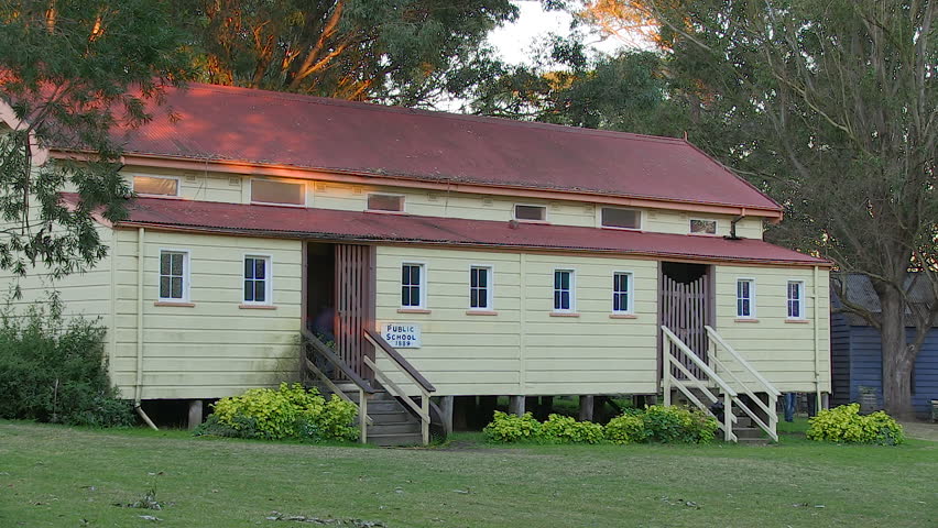 A medium shot of a house and grass field with trees