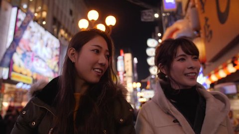 Two friends walking through bright Japanese streets dotombori 