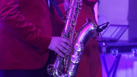 a male saxophonist with a musical band playing on stage in a restaurant, a saxophonist playing, shallow depth of field