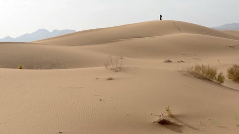 desert, a lonely girl walks along the sand dunes
