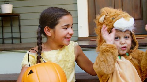 Children In Halloween Costumes For Trick Or Treating On Steps