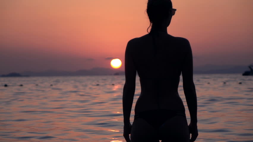 Silhouette of woman admire sunset standing in sea, super slow motion 240fps 
