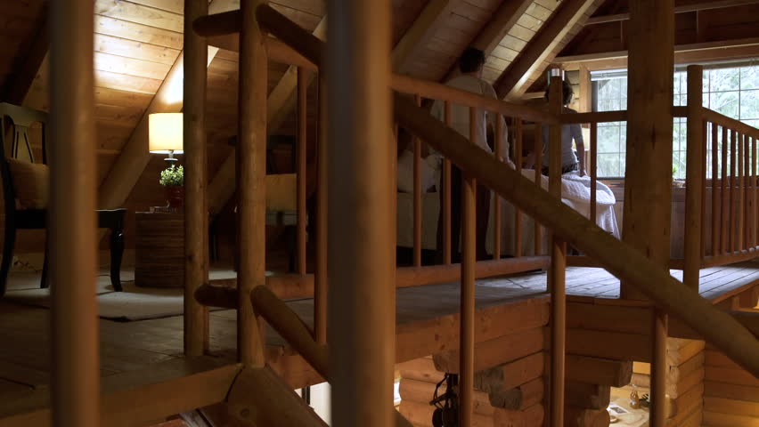 Mid adult couple making bed in a log cabin