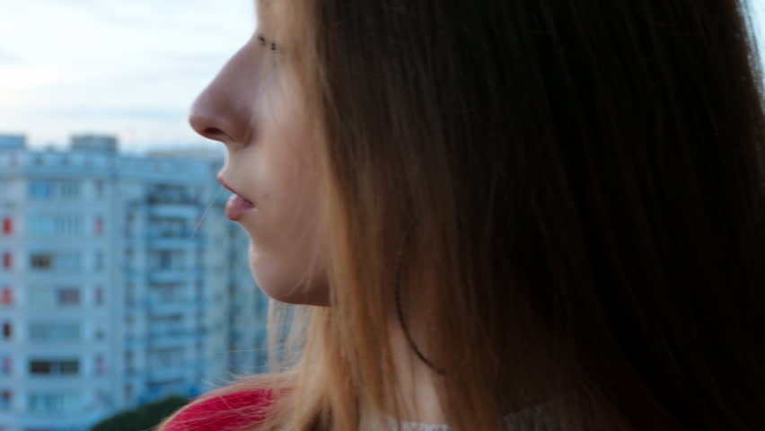 Beautiful young student girl with a perfect manicure standing on the terrace on the background of an amazing architecture. Pretty girl with wistful gaze taking a cup of tasty hot coffee
