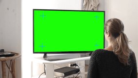 Young Woman Watching TV Zoom In. Young woman watching big screen television at home, zoom in. Green screen footage