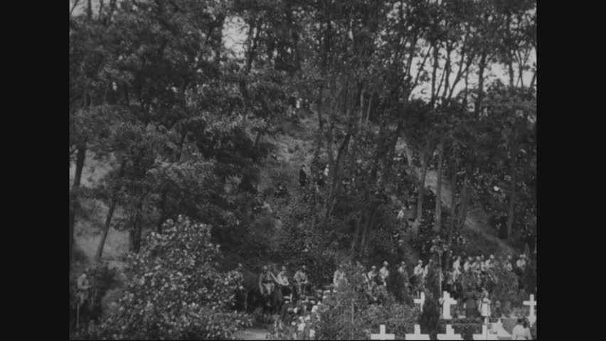 CIRCA 1920 - An American flag flies at half-mast and mounted troops and families are shown at Suresnes Cemetery in France.