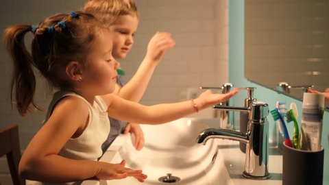 Sister and brother children in bathroom washing hands in evening family at home