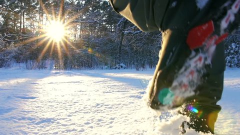 Hiking in the deep snow in winter. Close-up of feet walking in snowy mountain forest on sunset. Winter Journey Adventure.