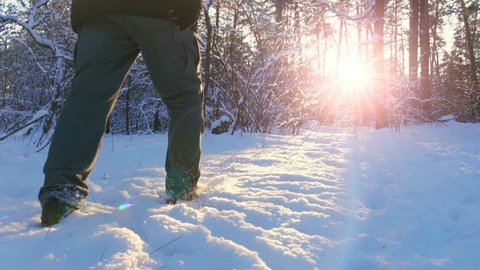 Hiking in the deep snow in winter. Close-up of feet walking in snowy mountain forest on sunset. Winter Journey Adventure.