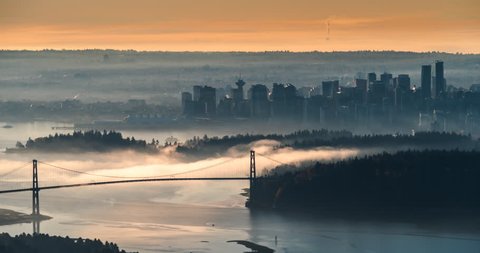 Fog moving over the ocean during sunrise under the Lionsgate Bridge. Vancouver city skyline in the backrgound, this is the viewpoint from Cypress Mountain.

