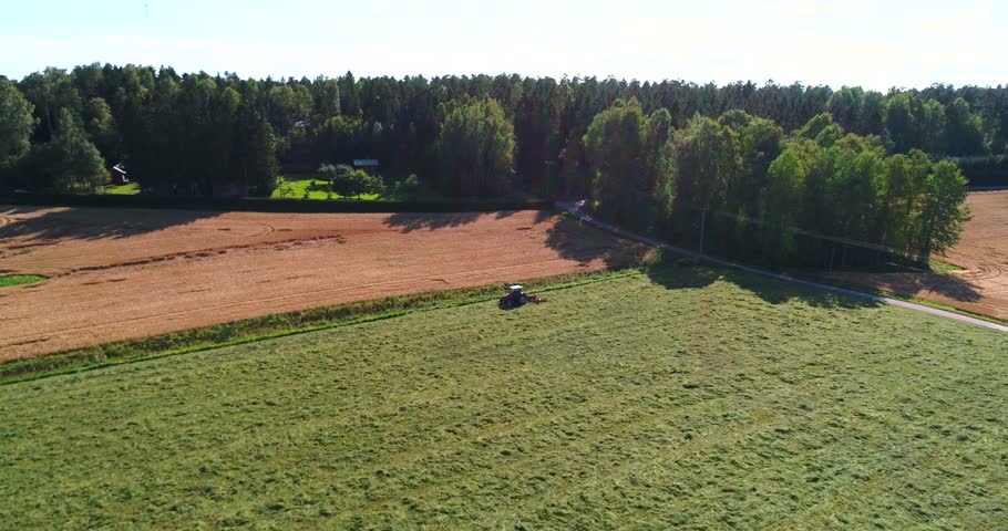 Plow tractor, Cinema 4k aerial tilt view towards a plowing machine, harvesting on a grass field, on a sunny autumn day, in Uusimaa, Finland 