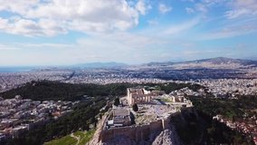 Aerial drone bird's eye view rotational video of iconic Acropolis hill and the Parthenon with beautiful scattered clouds, Athens historic center, Attica, Greece