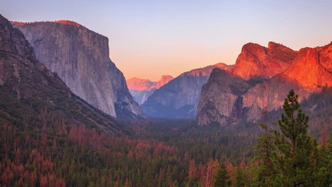 Yosemite National Park at iconic Tunnel View overlook. Front view of popular El Capitan and Half Dome at sunset in California, United States. Sunset time lapse with changing light to dark night.