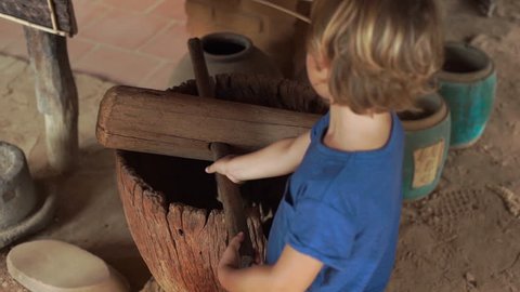 Slowmotion shot of a little boy visiting exposition in national museum on Phu Quoc island Vietnam, he looks at an ancient agricultural instruments