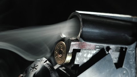 Smoke from the trunks of smooth-bore hunting rifle after firing. Slow motion. Black background.