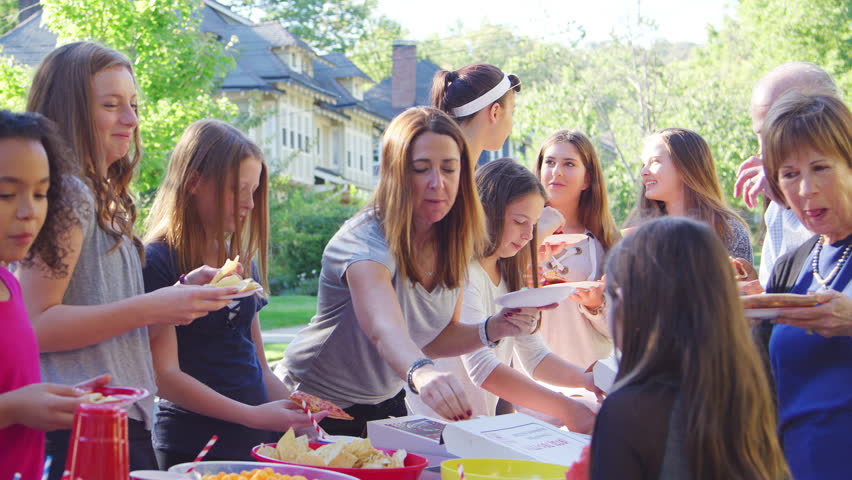 Neighbours stand eating at table at a block party, close up