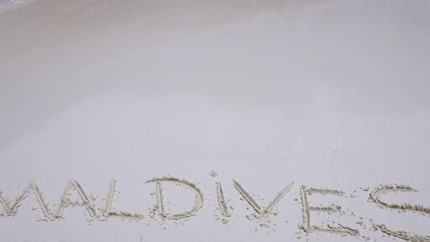 Handwriting word "Maldives" on maldivian beach drawn on sand, travel destinations concept