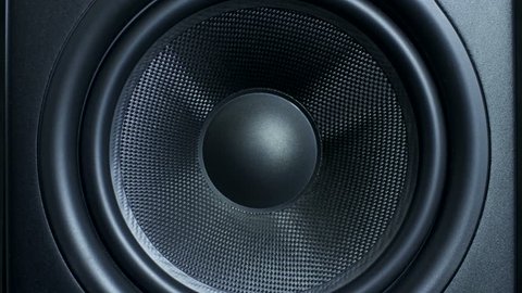 Close-up of black round audio speaker pulsating and vibrating from sound on low frequency. Contemporary stylish sub-woofer.