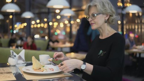 A middle-aged woman eats dessert in a cafe.