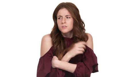 Portrait of adult woman with brown hair hesitating and rubbing her palms trying to choose or decide, over white background. Concept of emotions