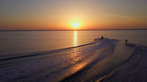 Jet ski rides water skiing man in the sunset drone footage