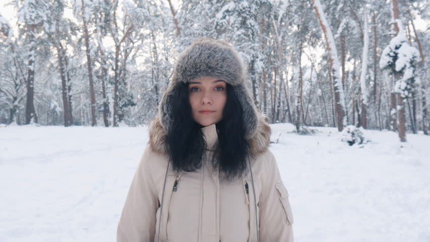 portrait of beautiful young in hat woman at winter snowy forest