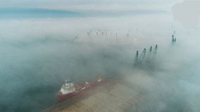 Aerial drone view of cargo ship and cranes in fog in the sea harbor. Sea port Varna. Bulgaria