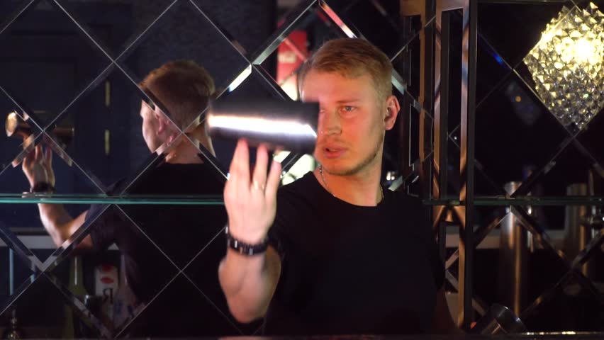 The bartender performs tricks with bottles and glasses Slow-mo