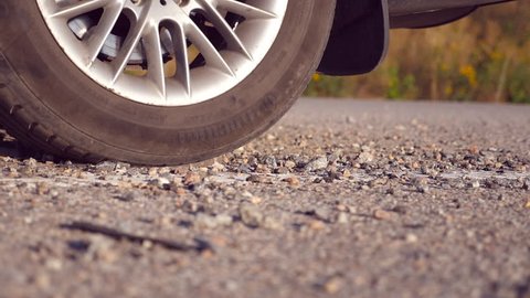 Wheel of car are slip on a asphalt road during start of movement. Small stones and dirt is fly out from under the tire of a auto. Slow motion close up