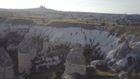 Ascending high angle aerial view of Cappadocia fairy chimney landscape near Goreme town and Uchisar Castle in background, Turkey. 4K