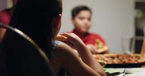 Hispanic family with mom, fat son and daughter having dinner at home, eating salad and pizza. 