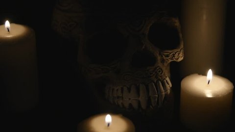 four lighted candles and a skull on a black background. close up