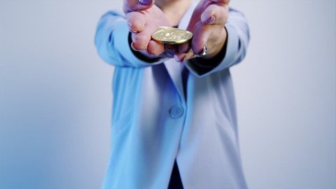 fashion woman in business suit holding golden coin bitcoin in hand, blured portrait smiling woman