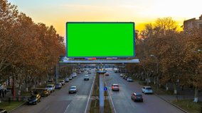 A billboard with green chroma key on the background of fast moving cars at sunset. 4K Time Lapse video