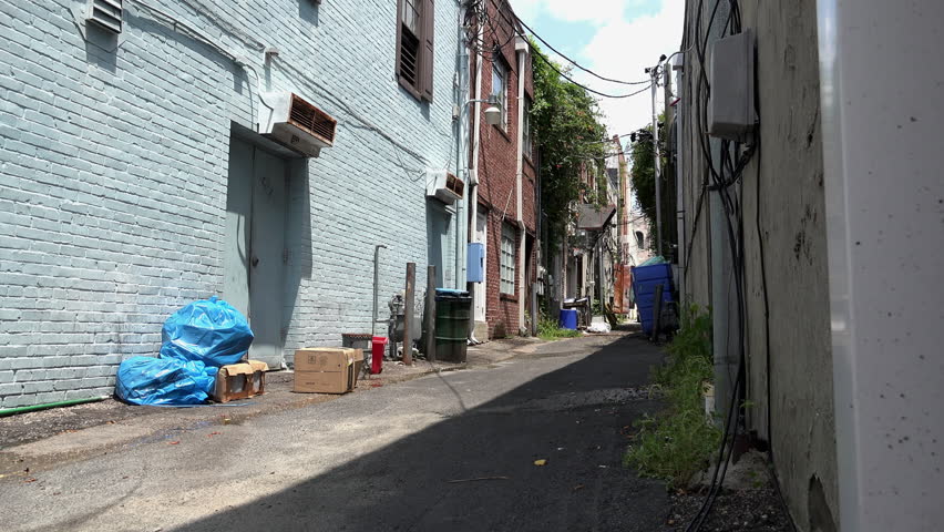 Alley with clutter and litter in it behind stores 4k