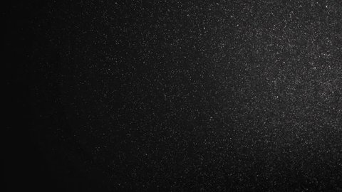 Floating organic dust particles shimmering on a black background. Particles swirling randomly as if blown by wind Particles moving quickly through space, each particle independently Dynamic particles.