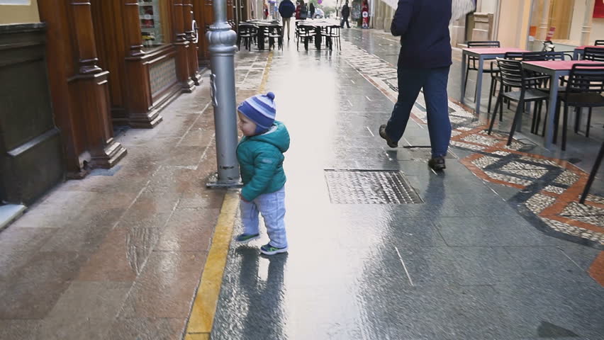 Baby stands near the door and wants to go to the souvenir shop.