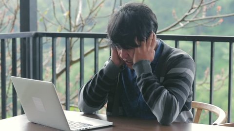 Man feeling stress in front of laptop / computer in the cafe