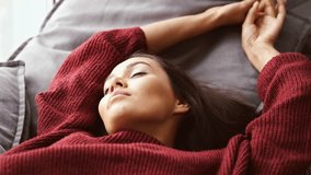 Close up view of Smiling brunette woman in sweater lying on bed at home