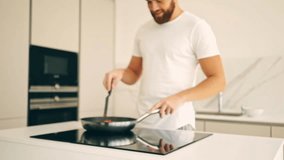 Cropped view of smiling bearded man cooking vegetables on stove at kitchen
