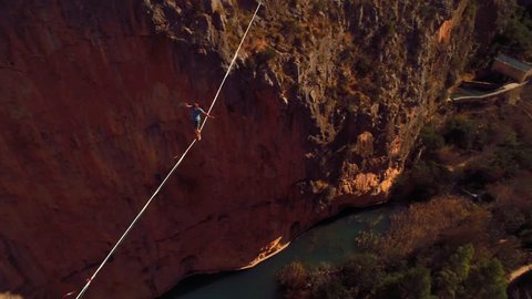 Young Man Slacklining , highlining above a big canyon in Chulilla , Spain . Nature Adventure and leisure sport . Mountain Balance Extreme Hiker Walking Happy, 4k aerial cinematic footage