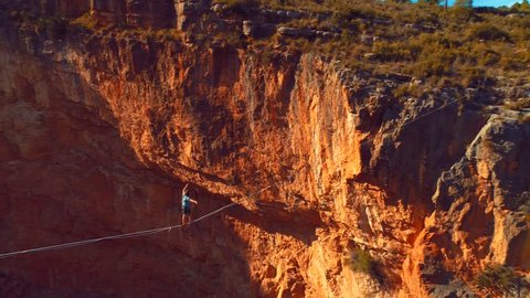 Brave Man Slacklining , highlining above a big canyon . Nature Adventure and leisure sport . Mountain Balance Extreme Hiker Walking Happy, 4k aerial slow motion