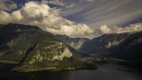 Time lapse of late afternoon clouds moving over Hallstätter See in Austria with alpine villages and mountains in the distance.