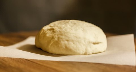 time lapse. the dough rise . yeast dough rising on parchment on wooden table, on dark background. stages of cooking pizza. pizza dough