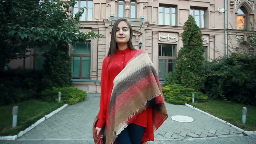 Charming young woman with a magnificent brunette hair, big eyes, gorgeous red lipstick and stylish look. Attractive young lady is rushing in the city-center, she turns to camera and smiles.