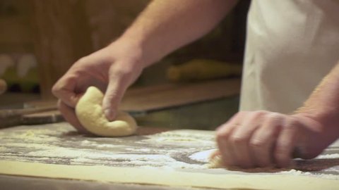 Making pizza or pide dough by close up male hands in pastry kitchen. Shaping dough is precursor to making a wide variety of food stuffs, particularly breads, biscuits, cakes. Slow motion video.