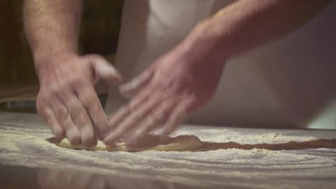 Making pizza or pide dough by close up male hands in pastry kitchen. Shaping dough is precursor to making a wide variety of food stuffs, particularly breads, biscuits, cakes, cookies, dumplings, pasta