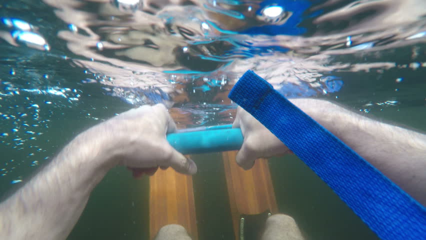 POV of a water skier floating above and below water waiting to go water skiing wearing vintage wooden water skis in a lake