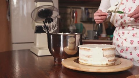 close up shot of the chef's hands, a woman lubricates the cream cake with a knife, the lady attaches an even shape to a sweet dessert that will be sold Stock Video