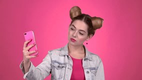 Girl doing selfie. Pink background. Slow motion